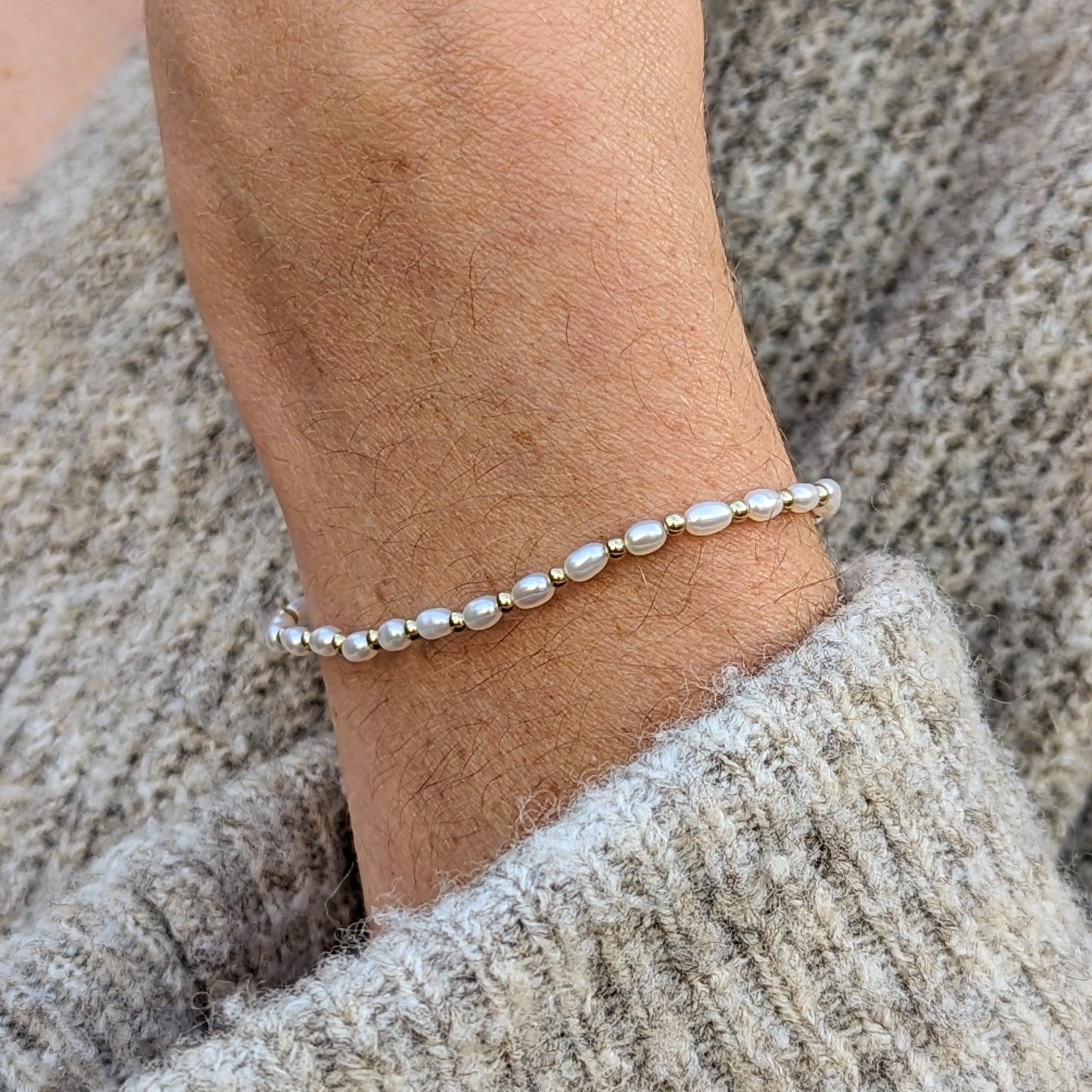 Closeup of wrist wearing a tiny pearl and gold bead bracelet