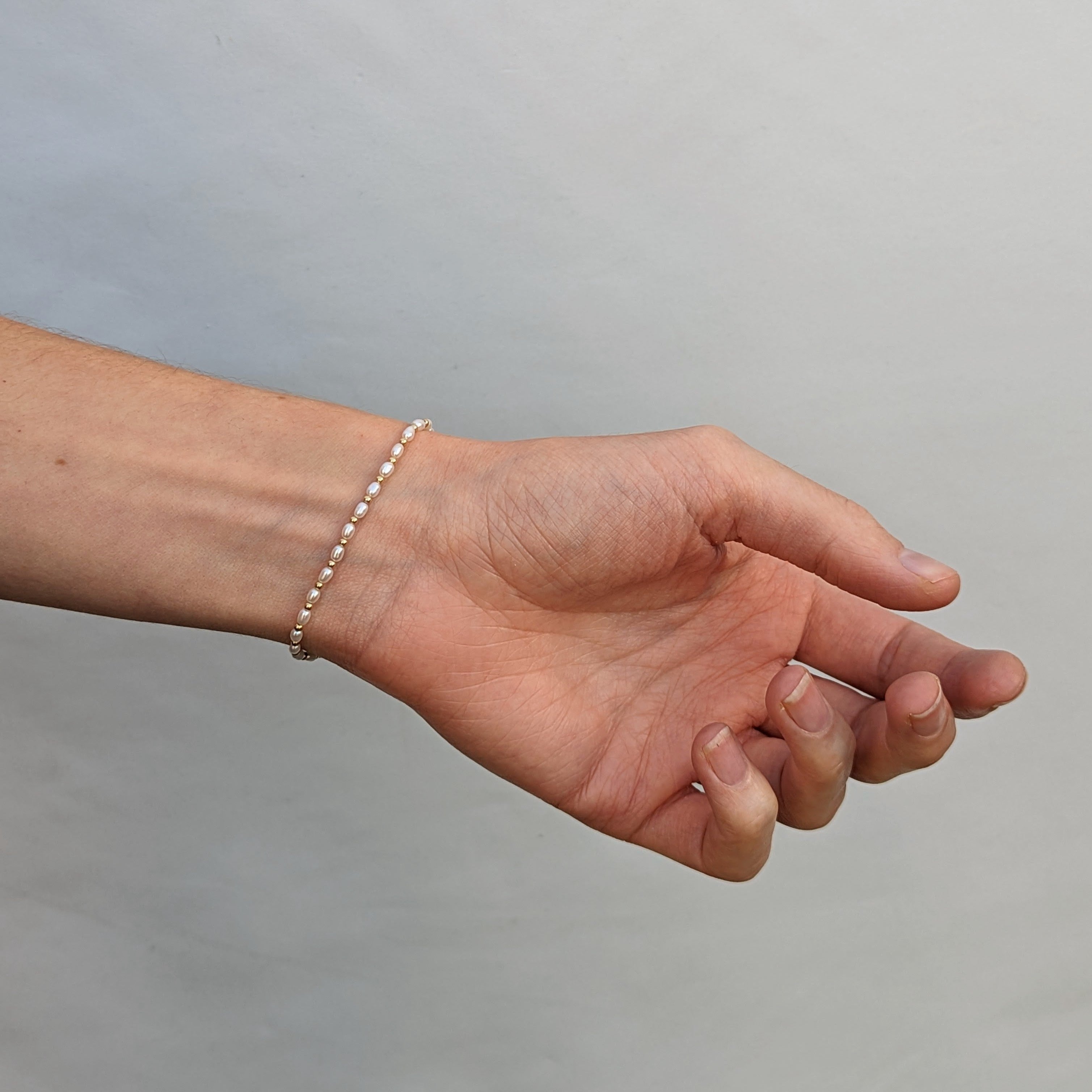 Hand and wrist wearing a small pearl and bead bracelet
