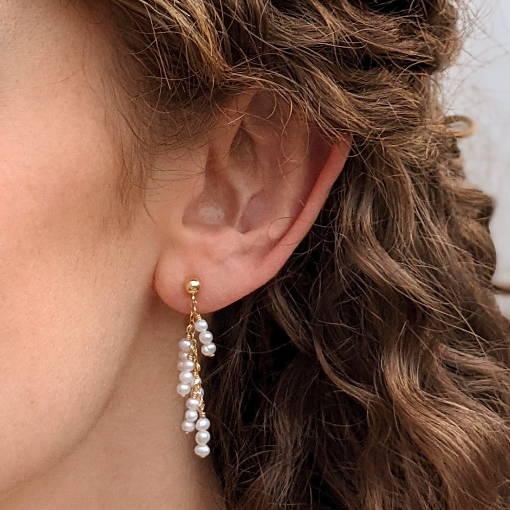 Model wearing tiny pearl drop earrings from gold ball stud