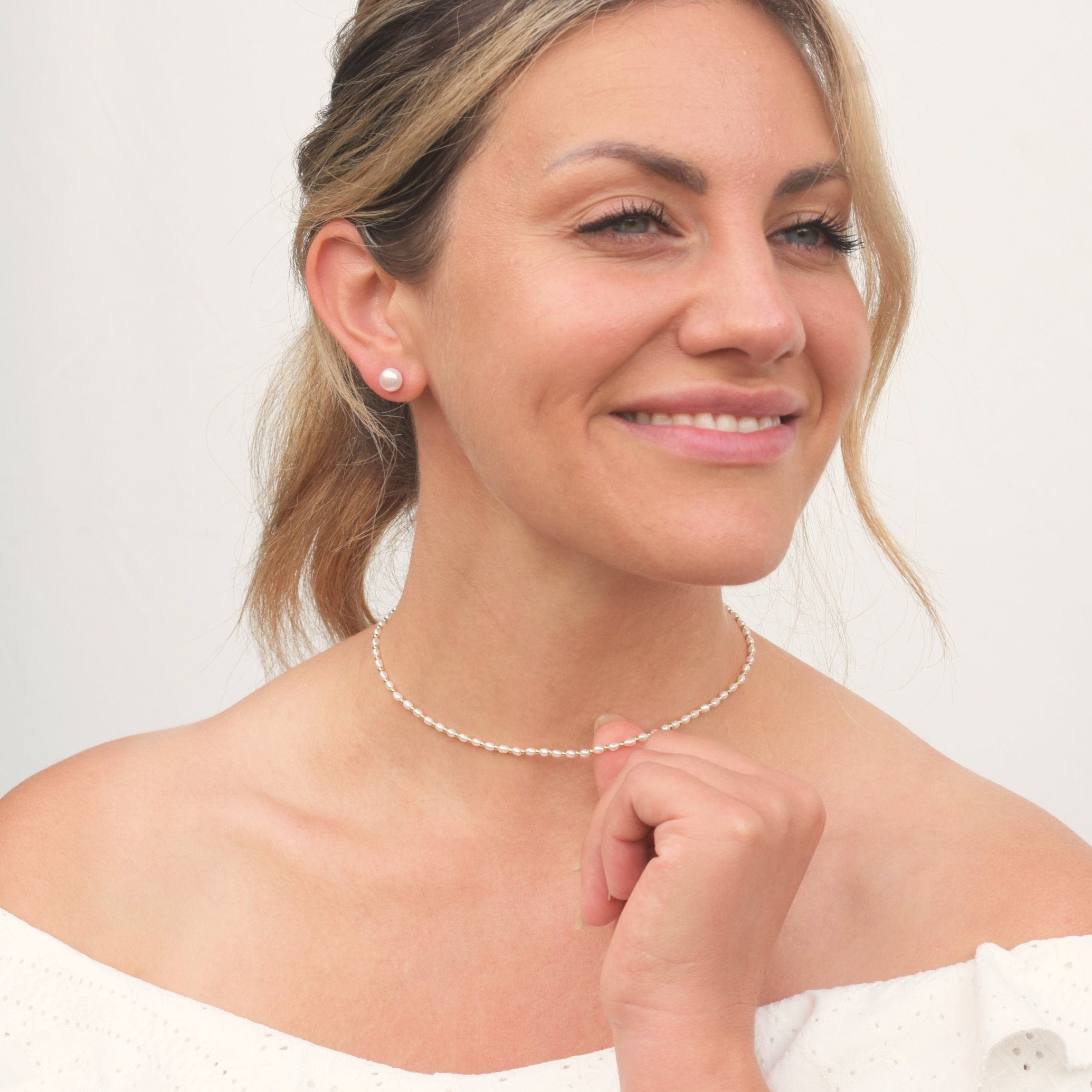 Model wearing pearl and gold bead necklace and pearl earrings