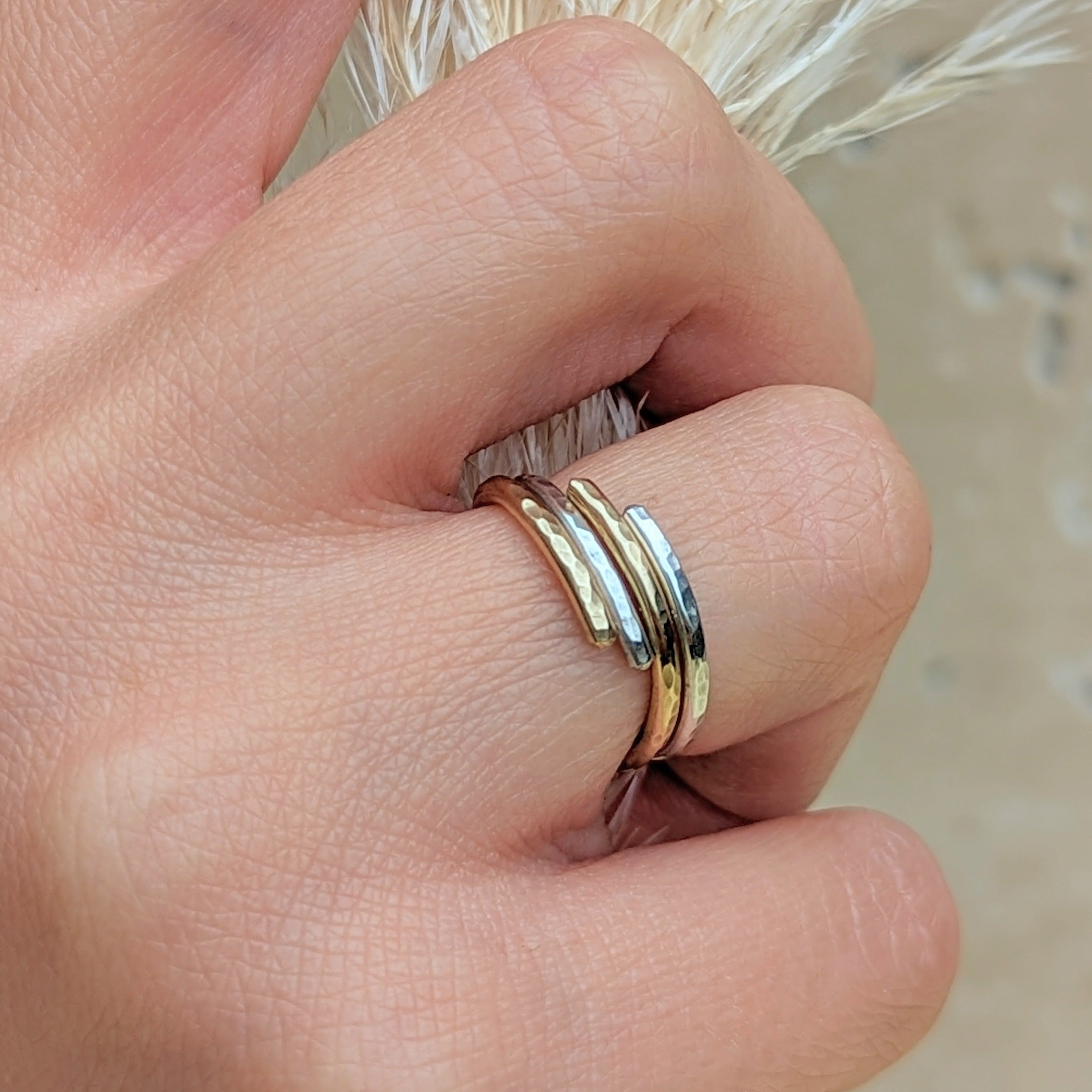 Intertwined mixed metal ring stack silver and gold on hand closeup